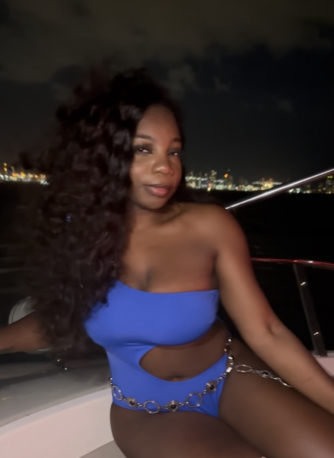Miss Coco aboard a yacht with the city skyline glowing behind her